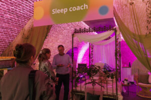 Sleep coach guiding a relaxing group session at an event with calming lights and mindfulness atmosphere