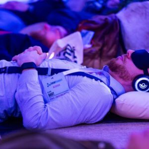 Participants wearing glowing headphones during a 9D Breathwork event, experiencing a multi-dimensional sound healing and guided meditation session in a darkened, atmospheric room